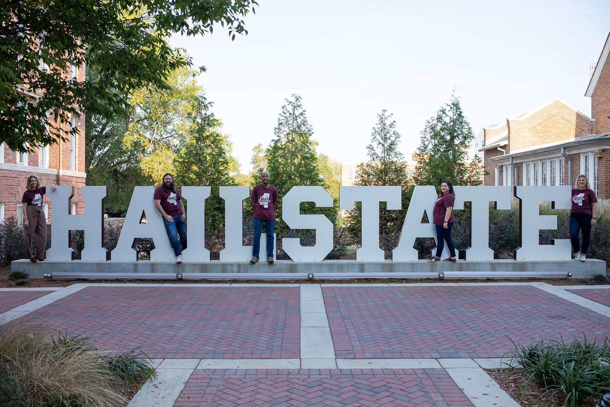 The ID team standing on a statue that spells out Hail State